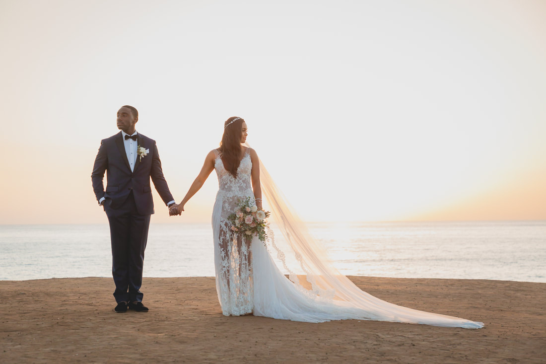 Married couple holding hands on a cliff during sunset hours taken by San Diego Wedding Videographer One in a Million Films